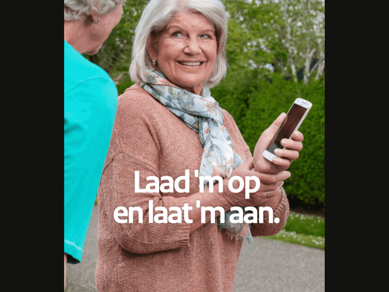 Vrouw heeft mobiele telefoon in haar hand en op de afbeelding is tekst te lezen: 'Laad 'm op en laat 'm aan.'